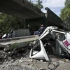 Nhân viên cứu hỏa chuyển một chiếc xe ôtô bị phá hủy bên một chiếc cầu bị sập do động đất tại Mexico ngày 20/3. (Nguồn: AFP/TTXVN)