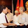 Tổng giám đốc Thông Tấn Xã Việt Nam Nguyễn Đức Lợi trao sổ tiết kiệm cho thân nhân liệt sỹ tại Lễ kỷ niệm. (Ảnh: Quốc Khánh/TTXVN)