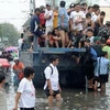 Ôtô chở người dân khỏi vùng ngập lụt ở Navotas, ngoại ô Manila ngày 2/8. (Nguồn: AFP/TTXVN)