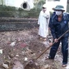 Người dân đào một khu vực chôn các thùng thuốc trừ sâu đã hết hạn. (Ảnh: Trịnh Duy Hưng/TTXVN)