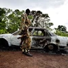 Một binh sĩ lực lượng quân đội giải phóng Nhân dân Sudan bên chiếc xe bị đốt cháy trong cuộc phục kích các phiến quân. (Nguồn: AFP/TTXVN)