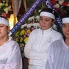 Bà Trần Thúy Liễu (giữa) và hai con trong đám tang nhà báo Hoàng Hùng. (Nguồn: Người Lao động)