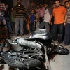 Người dân Palestine bên chiếc xe bị phá hủy trong cuộc không kích của Israel ở Gaza đêm19/8. (Nguồn: AFP/TTXVN)