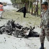 Binh sỹ Pakistan bên xác chiếc xe ôtô tại hiện trường vụ đánh bom. (Nguồn: AFP/TTXVN)