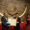 Đại sứ Dương Chí Dũng trao tặng Huy chương Hữu nghị cho giáo sư Michel Guillou. (Ảnh: Trung Dũng/Vietnam+)