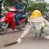 Công nhân môi trường phải dùng dao chém xuống mặt đường để cậy đất. (Ảnh: Trung Hiền/Vietnam+)