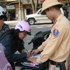 Cảnh sát giao thông đang xử phạt một trường hợp vi phạm theo Nghị định 34 của Chính phủ. (Ảnh: Mạnh Hùng/Vietnam+).