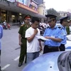Lực lượng Thanh tra đang tiến hành xử phạt xe taxi vi phạm. (Ảnh: Mạnh Hùng/Vietnam+)