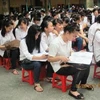 Sĩ tử tranh thủ xem lại kiến thức ngay lúc ngồi nghe quy chế thi tốt nghiệp. (Ảnh: Nhóm PV/Vietnam+)