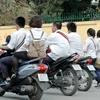 Học sinh đi xe máy dàn hàng ngang, không đội mũ bảo hiểm. (Ảnh: Văn Điệp/TTXVN)