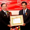 Ông Bounpon Buttanavong trao Huân chương cho anh hùng Lao động Lê Văn Kiểm. (Ảnh: Hoàng Chương/Vietnam+)