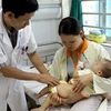 Khám và điều trị cho trẻ bị bệnh chân tay miệng. (Ảnh: Dương Ngọc/TTXVN)