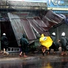 Lực lượng cảnh sát cơ động giúp đỡ một hộ dân vừa bị bão làm sập mái hiên nhà. (Ảnh: Thế Lập - Ly Kha/TTXVN)