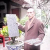 Đại đức Thích Thanh Vịnh giới thiệu một vài trang sách trong số hơn 3.000 bản mộc được khắc trên gỗ thị. (Nguồn: baobacgiang.com.vn)