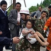 Nhân viên cứu hộ đưa một em bé ra khỏi ngôi nhà sập sau trận động đất ở tỉnh Tứ Xuyên. (Nguồn: THX/TTXVN)