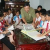 Ông Đào Thông giới thiệu bộ sưu tầm về Bác Hồ cho học sinh trường Tiểu học số 2-Bảo Ninh, tỉnh Quảng Bình. (Ảnh: Ngọc Châu/Vietnam+)