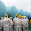 Nhân viên của Bộ điều chỉnh hạt nhân Nhật Bản gần các thùng chứa nước phóng xạ tại nhà máy điện Fukushima Daiichi. (Nguồn: EPA)
