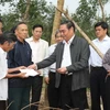 Ông Lê Hồng Anh trao tiền hỗ trợ cho các hộ có vườn cao su bị gãy đổ nặng tại xã Vĩnh Thủy, huyện Vĩnh Linh. (Ảnh: Hồ Cầu/TTXVN)