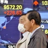 Hai thương gia đi ngang qua bảng giá cổ phiếu ở Tokyo ngày 1/12. (Ảnh: Daylife)
