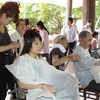 Các thành viên của đoàn đang cắt tóc miễn phí cho người khuyết tật. (Ảnh : Hữu Việt/TTXVN) 