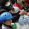Các bà mẹ nhận nước uống tại văn phòng bảo trợ ở Tokyo ngày 24/3. (Nguồn: AFP/TTXVN)