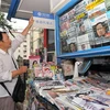 Một chủ sạp báo ở Bắc Kinh gỡ tấm bản chào bán sim điện thoại di động. (Nguồn: Chinadaily)