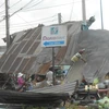 Người dân đang thu dọn mái tôn bị sập. (Ảnh: Lê Linh/Vietnam+)