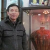 Nghệ nhân Trần Độ bên cạnh sản phẩm gốm men đỏ, một loại men hỏa biến cực khó tạo. (Ảnh: Phạm Mai/Vietnam)