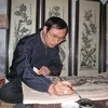 Nghệ nhân Nguyễn Hữu Quả vẽ tranh Đông Hồ tại Trung tâm thông tin phố cổ. (Ảnh: Thiên Linh/ Vietnam+)