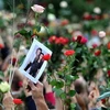 Người dân giơ cao những bông hồng và ảnh của nạn nhân trong vụ xả súng đẫm máu. (Nguồn: Xinhua) 