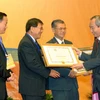 Chủ tịch Ủy ban Trung ương MTTQ Việt Nam Huỳnh Đảm trao Bằng khen của Bộ Ngoại giao cho các kiều bào có công với đất nước. (Ảnh: Nhan Sáng/TTXVN) 