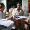 Nhà thơ Hồ Trung Việt (trái) bận rộn với những bản thảo thơ. (Ảnh: baoquangnam)