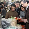 Kiểm tra nhãn mác, hạn sử dụng của bánh kẹo bày bán trong chợ Đồng Xuân. (Ảnh: Hữu Oai/TTXVN)