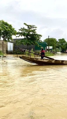 Người dân xã Kim Hoa, huyện Hương Sơn sử dụng thuyền để di chuyển trong vùng ngập nước. (Ảnh: Hữu Quyết/TTXVN)