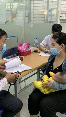 Phụ huynh đưa trẻ đi tiêm vaccine phòng bệnh sởi. (Ảnh: Đinh Hằng/TTXVN)