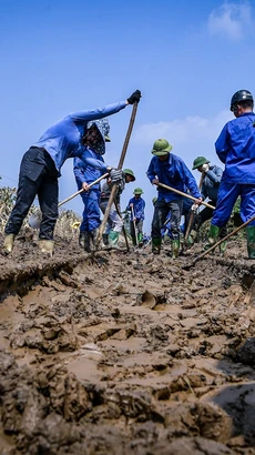 Công nhân viên đường sắt dọn dẹp bùn đất ở đường ray để đảm bảo chạy tàu. (Ảnh: PV/Vietnam+)