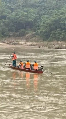 Lực lượng chức năng dùng xuồng máy, mở rộng phạm vi về phía hạ lưu sông Nậm Mộ gần 10km để tìm kiếm các nạn nhân. (Ảnh: TTXVN phát)