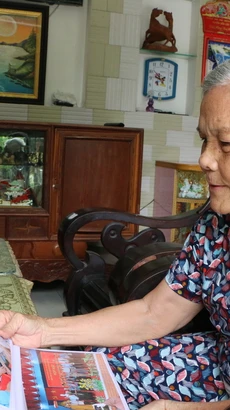 Bà Chín Xinh xem lại hình ảnh hoạt động của Hội cựu kháng chiến. (Ảnh: Thanh Bình/TTXVN)