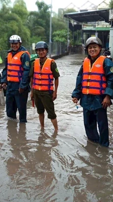 Lực lượng chức năng phường Tân Phước Khánh, thành phố Tân Uyên, tỉnh Bình Dương, có mặt để hỗ trợ người dân, phân luồng giao thông và cảnh báo những đoạn đường ngập sâu, nước chảy siết do mưa lớn. (Ảnh: TTXVN)