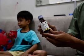 Một phụ huynh cầm chai thuốc ho con trai anh sử dụng dẫn đến tổn thương thận cấp tính tại Jakarta, Indonesia, ngày 11/2/2023. (Ảnh: AFP/TTXVN)