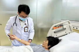 Bác sỹ Bệnh viện Đa khoa Thanh Vũ Medic Bạc Liêu kiểm tra vết ong đốt trên tay bệnh nhân T.H.C. (Ảnh: TTXVN phát)