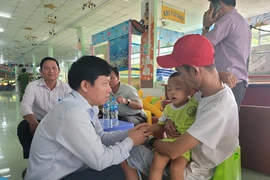Tiến sỹ Lê Quang Trí, Giám đốc Sở Giáo dục và Đào tạo tỉnh Tiền Giang (trái) thăm hỏi cháu bé vừa được giải cứu. (Ảnh: Minh Trí/TTXVN)