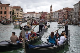 Khách du lịch đi thuyền gondola tại Venice, Italy. (Ảnh: AFP/TTXVN)