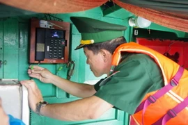 Lực lượng Biên phòng kiểm tra niêm phong, kẹp chì thiết bị giám sát hành trình trước khi tàu cà xuất bến đánh bắt hải sản trên biển. (Ảnh: Huỳnh Sơn/TTXVN)
