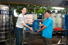 Những can nước sạch đầu tiên dành tặng bà con. (Ảnh: CTV/Vietnam+)