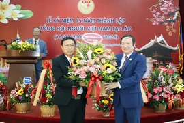 Đại sứ Việt Nam tại Lào Nguyễn Bá Hùng tặng hoa chúc mừng 15 năm thành lập Tổng hội. (Ảnh: Phạm Kiên/TTXVN)