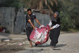 Người dân chuyển đồ đạc còn sót lại từ đống đổ nát sau cuộc không kích của Israel tại trại tị nạn Maghazi, Dải Gaza, ngày 15/4. (Ảnh: THX/TTXVN)