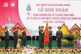 Trung tướng Nguyễn Anh Tuấn, Chính Ủy Bộ đội biên phòng gắn Huân chương Bảo vệ Tổ quốc hạng Nhất lên Cờ truyền thống của Cục Chính trị Bộ đội biên phòng. (Ảnh: Trọng Đức/TTXVN)