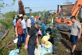 Người dân cùng lực lượng chức năng khắc phục sự cố công trình thủy lợi Ngũ Huyện Khê. (Ảnh: TTXVN phát)