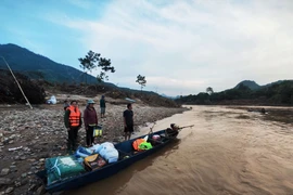 Các tình nguyện viên di chuyển bằng xuồng đến trao hỗ trợ cho người dân bản Cuông 2. (Ảnh: Phùng Nam Sương/TTXVN)